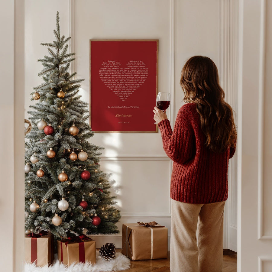 Frau vor dem Weihnachtsbaum betrachtet ein rotes Songtext-Poster in Herzform